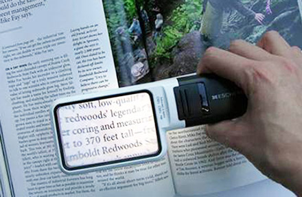 reading a book with an illuminated eschenbach handheld magniferer