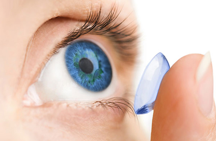 person inserting a contact lens into their eye